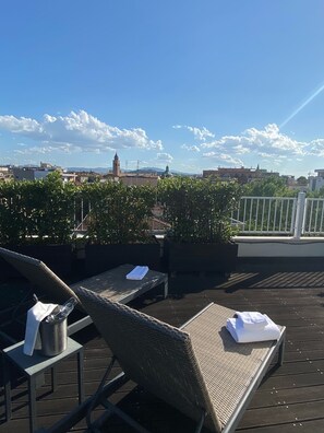 A rooftop terrace with wicker lounge chairs, a metal table, and potted plants. - Hotel Card International (Rimini)