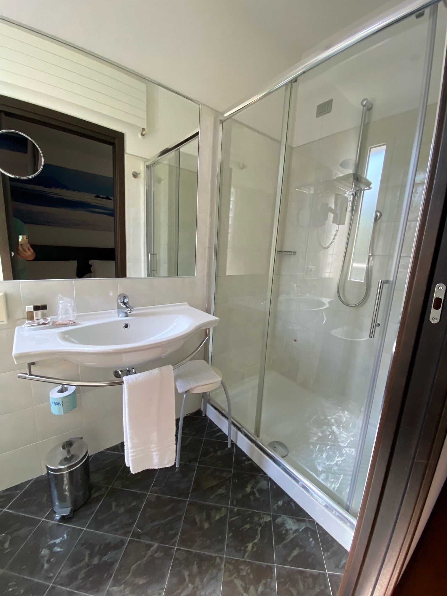 Ein Badezimmer mit einer Duschkabine, einem Waschbecken mit Spiegel und einer Toilette.