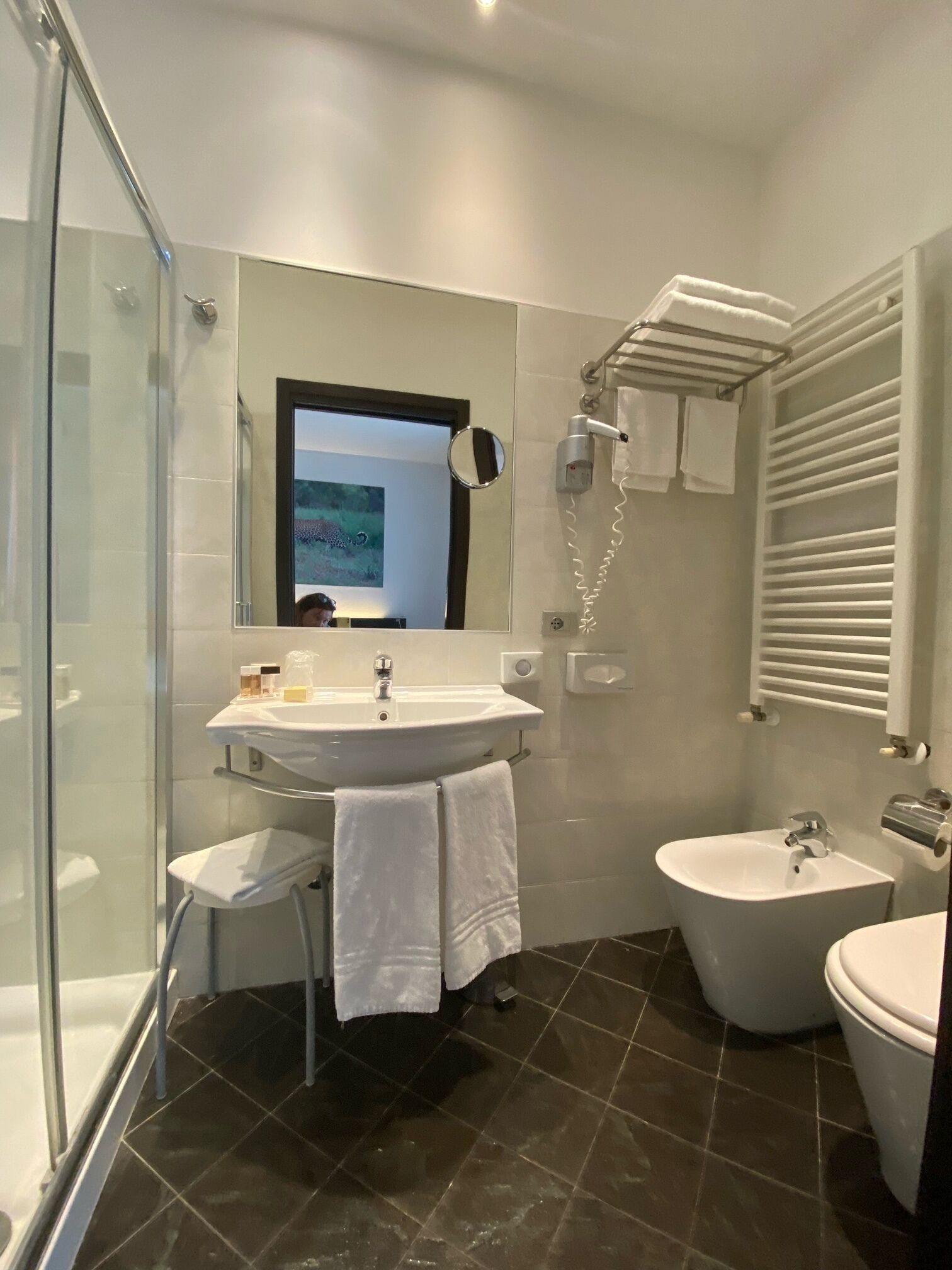 Un baño moderno con cabina de ducha de vidrio, un lavamanos con espejo, un bidé y un perchero para toallas.