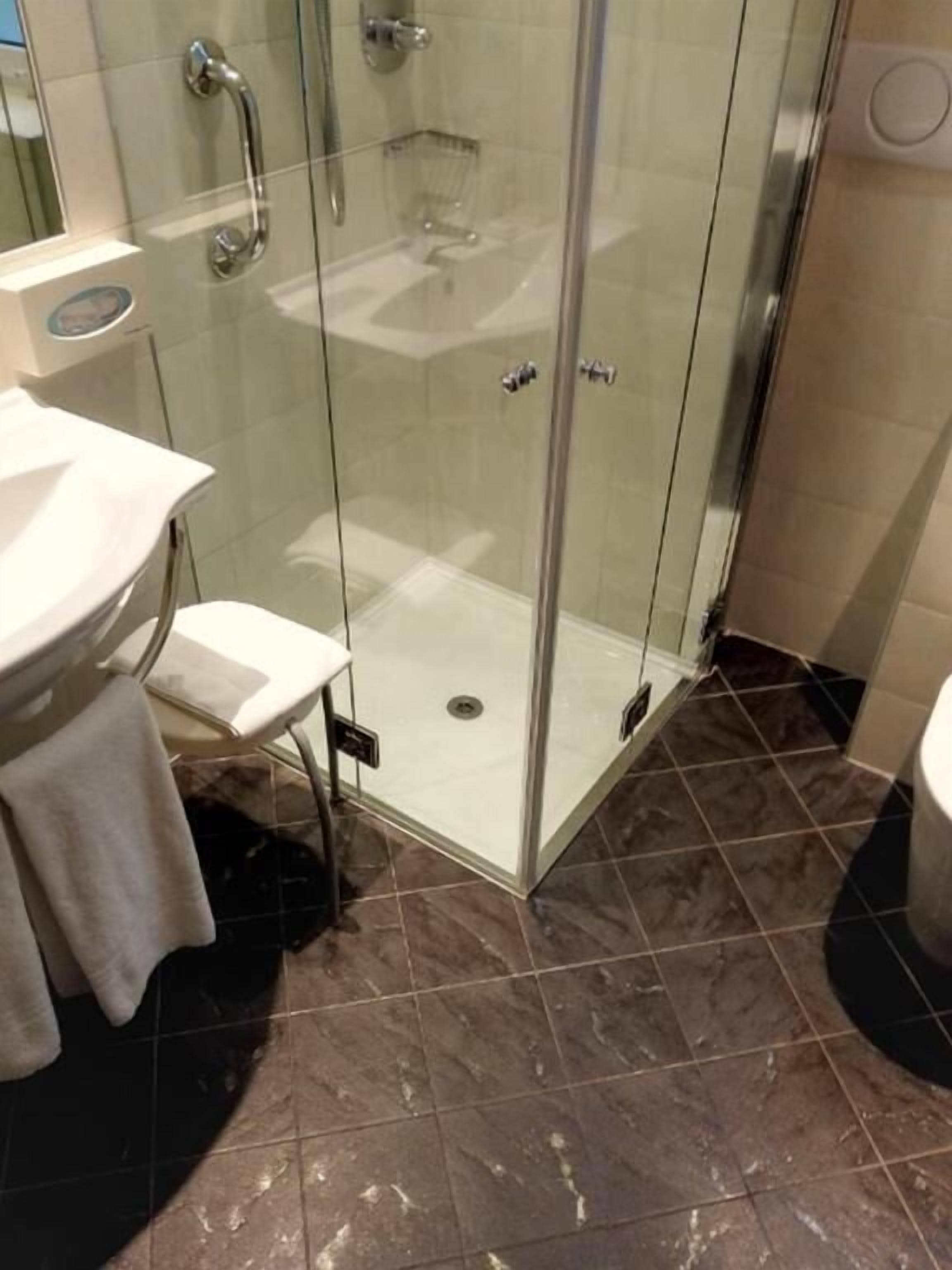 A bathroom with a glass shower enclosure, a sink, and a towel rack.