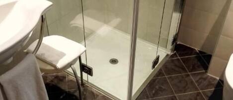 A bathroom with a glass shower enclosure, a sink, and a towel rack.