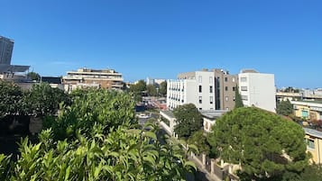 Un paisaje urbano con edificios modernos, un cielo azul despejado y árboles verdes frondosos en primer plano.