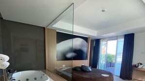 Un baño moderno con una bañera independiente, un espejo grande y una zona de estar con un banco.