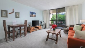 Ein Wohnzimmer mit einem Holztisch, Stühlen, einem Fernseher und einem Sofa.