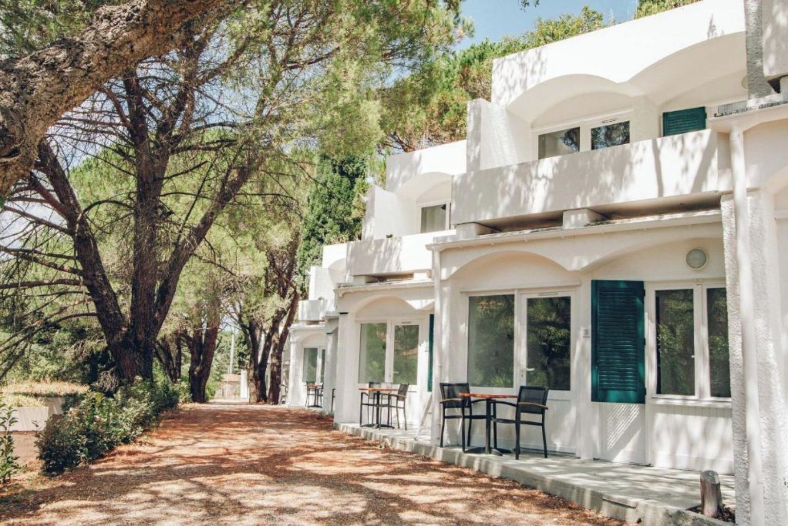 A row of white buildings with large windows and a paved pathway.