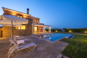 Une maison moderne dotée d’une piscine, d’un espace salon extérieur et d’une terrasse bien éclairée.