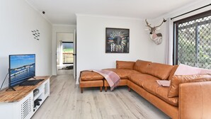 Una sala moderna con un sofá seccional, un televisor de pantalla plana y un adorno de pared decorativo.