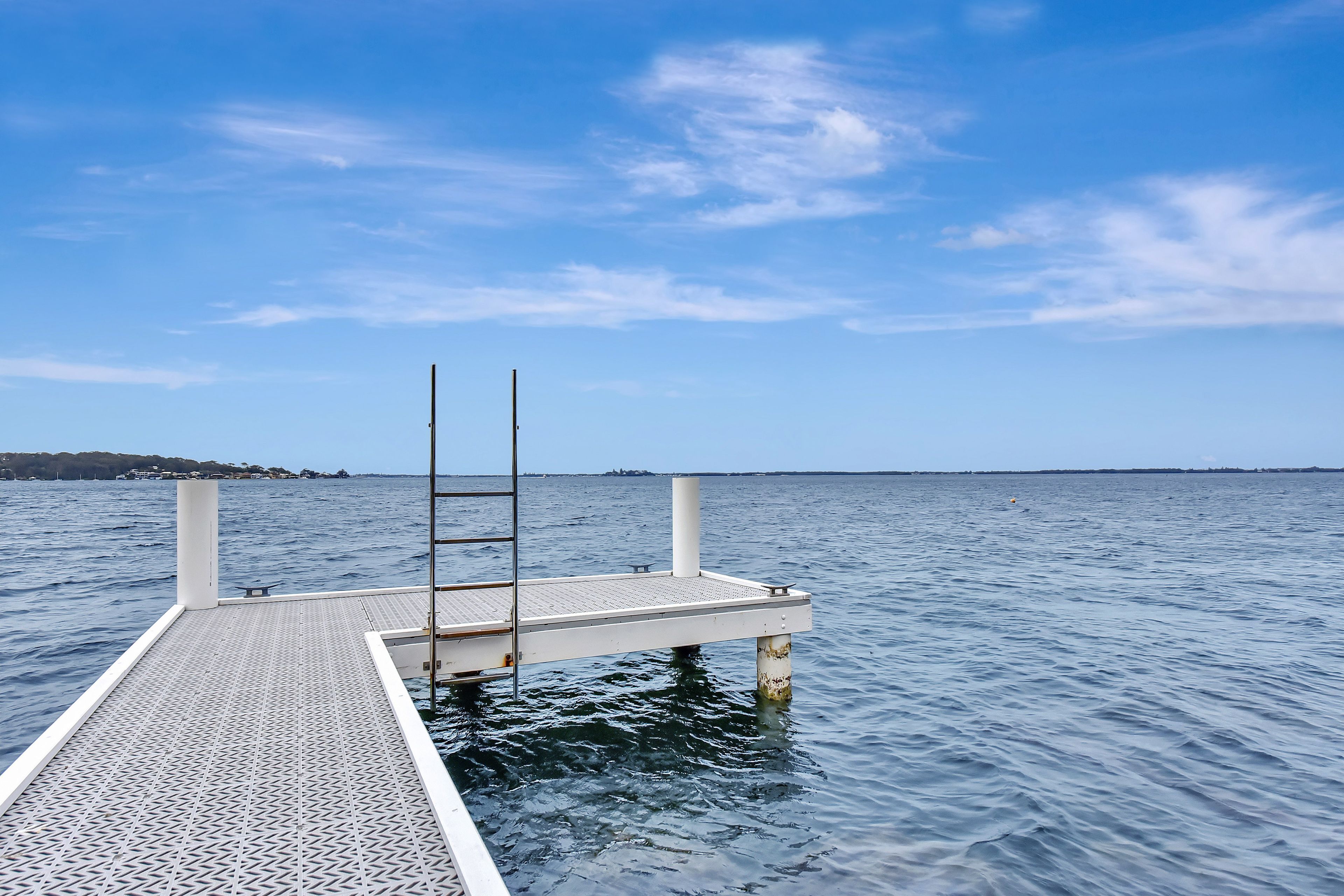 Un muelle que se adentra en aguas tranquilas bajo un cielo despejado.