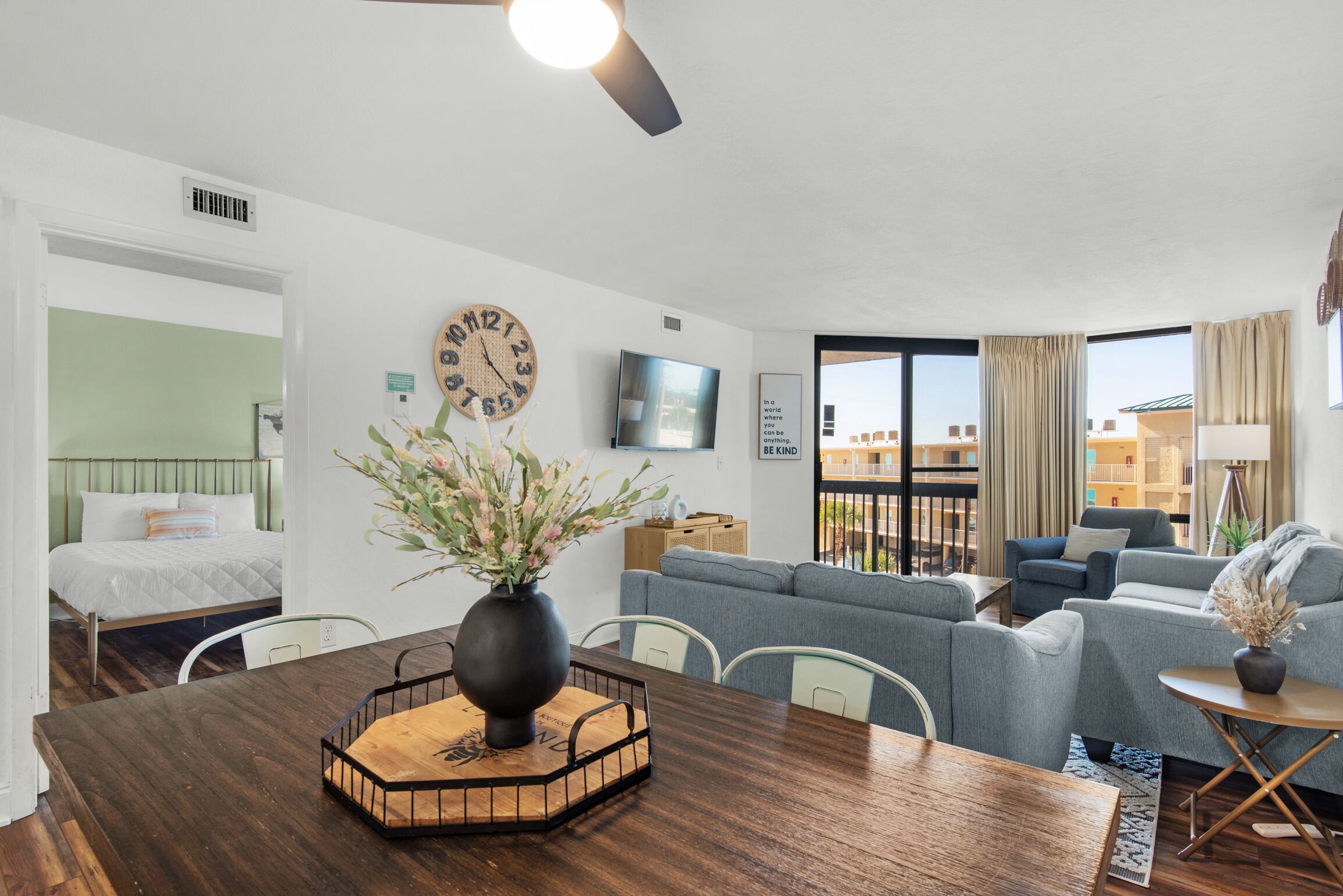 Une chambre d’hôtel moderne avec une table à manger en bois, un canapé, une télévision et un balcon offrant une vue agréable.