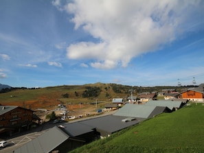 A ski resort with buildings, a parking area, and a mountain in the background.