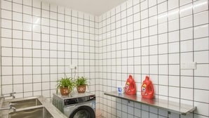 A small laundry area with a washing machine, two sinks, and a shelf with cleaning supplies. - Green Tree Inn Express Yangzhou Wanda (Yangzhou)
