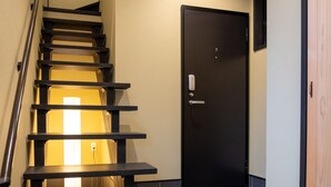 A staircase with a handrail leading to a door with a keyhole and a handle.