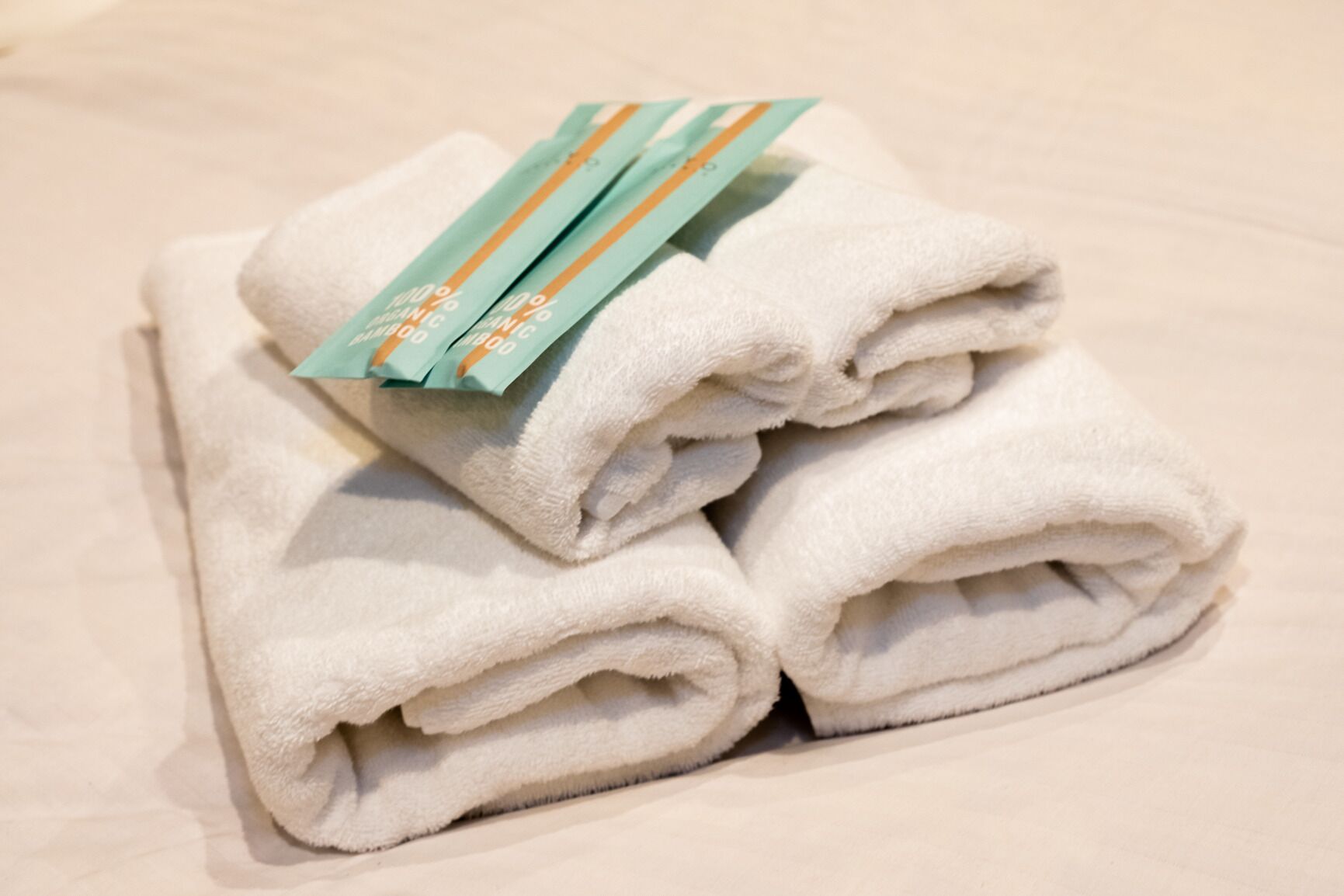 A stack of white towels with a green and orange tag on top.