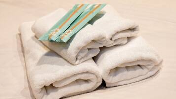 A stack of white towels with a green and orange tag on top.