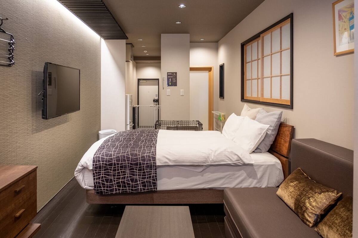Une chambre d’hôtel moderne équipée d’un lit, d’un canapé, d’une télévision et d’une fenêtre donnant sur un paysage agréable.
