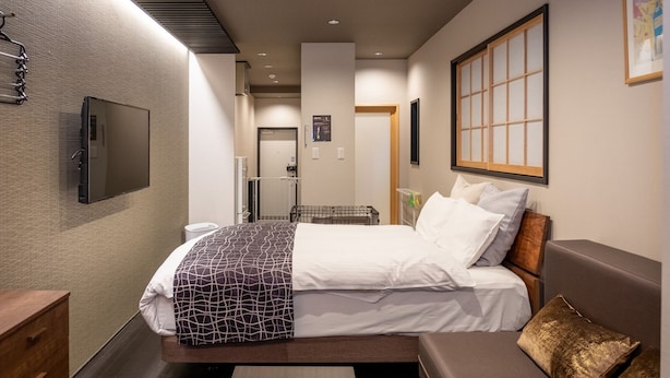 A modern hotel room with a bed, a sofa, a TV, and a window with a view.