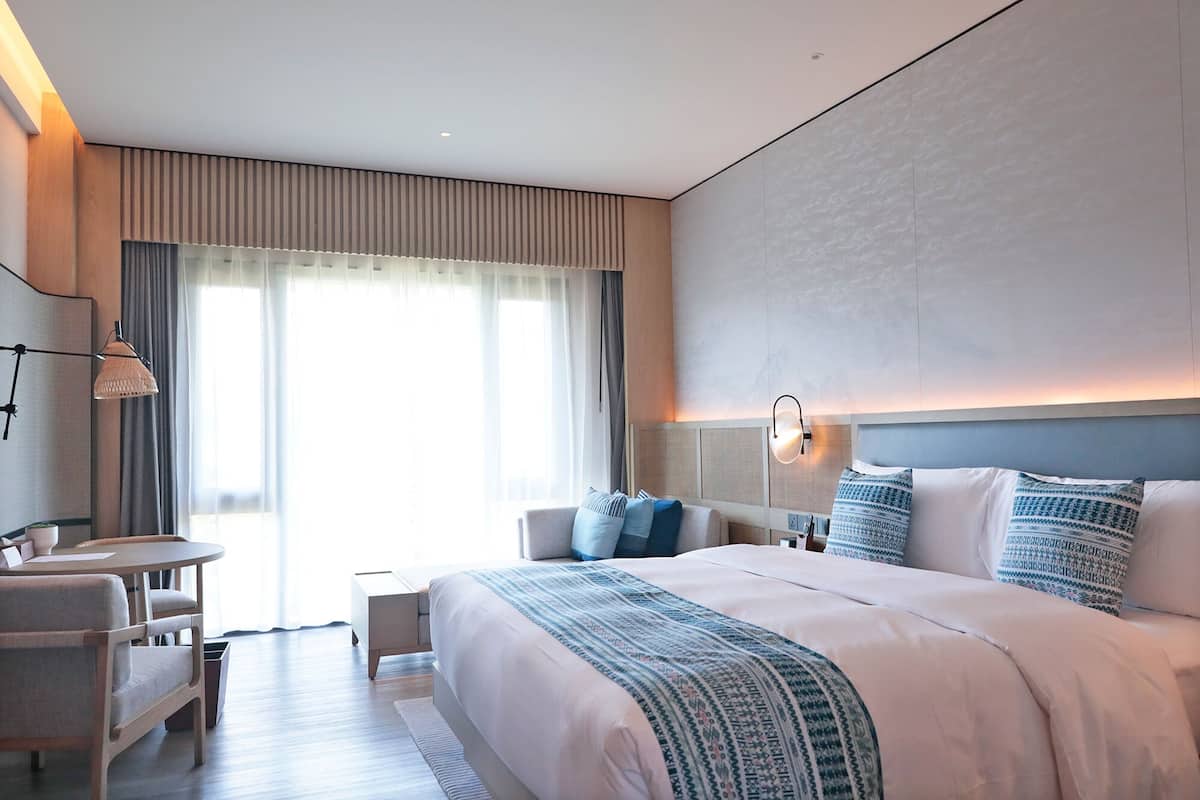 Une chambre d’hôtel moderne, dotée d’un grand lit, d’un bureau et d’une chaise.
