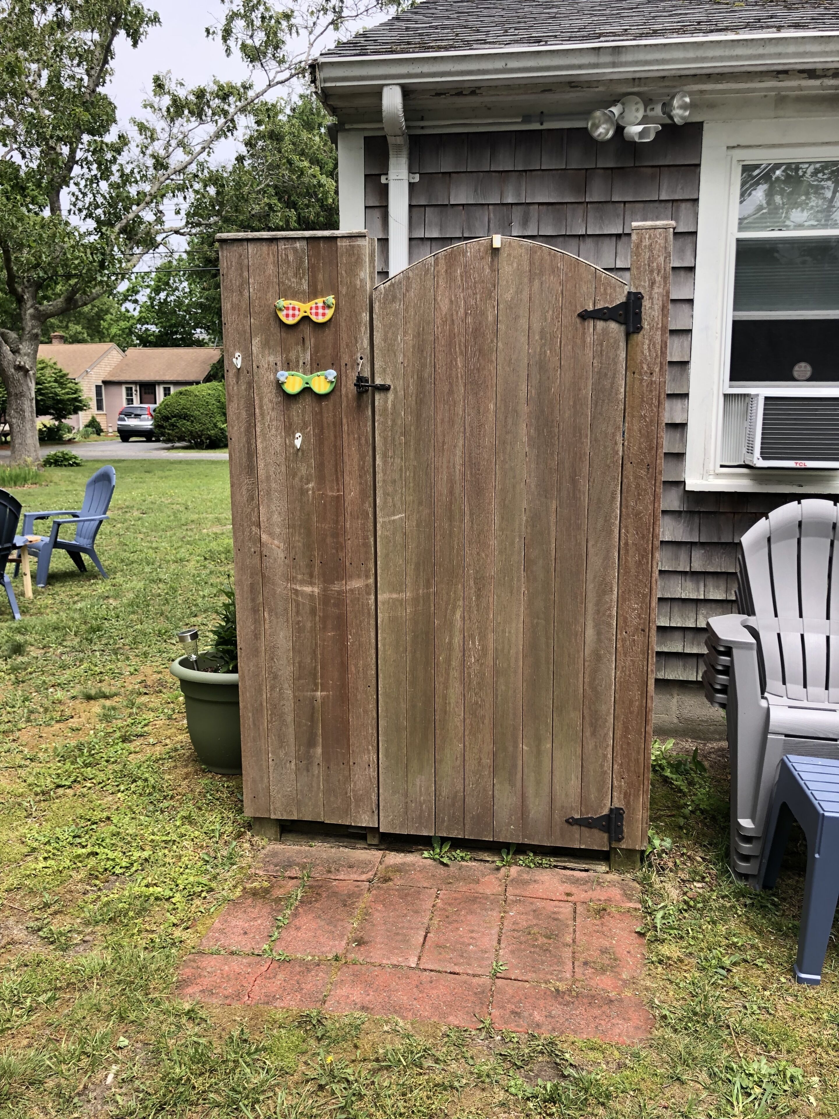 Une porte en bois agrémentée d’éléments décoratifs, un chemin pavé de briques et du mobilier d’extérieur.
