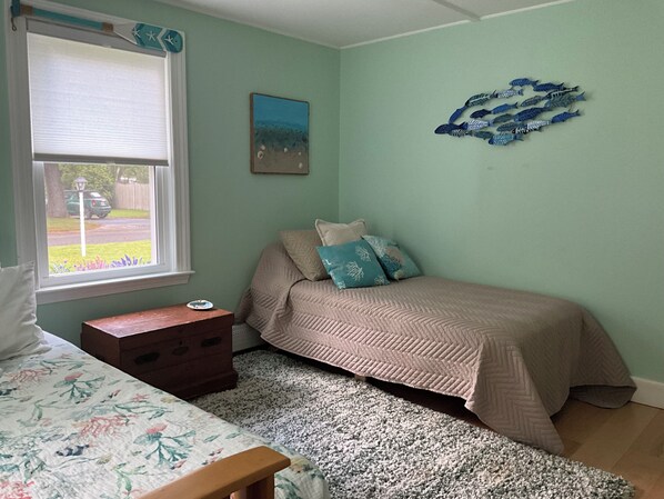 A bedroom with a bed, a dresser, a window with a view, and a wall decoration.