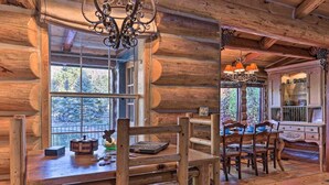 L’intérieur d’un chalet rustique, avec une table à manger en bois, des chaises et un lustre.