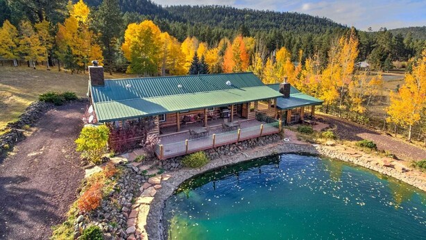 A lodge with a green roof, a stone foundation, and a pond in front. - Greer Lodge- Guest Quarters (Greer)