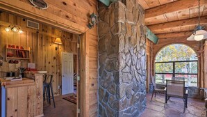 A rustic interior with a stone wall, wooden beams, and a bar area. - Greer Lodge- Guest Quarters (Greer)