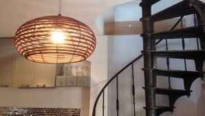 Een trap met een zwarte leuning en een ronde, geweven lamp erboven.