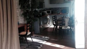 Een moderne keuken met een inbouwmagnetron, een eethoek met een tafel en stoelen, en een grote potplant.