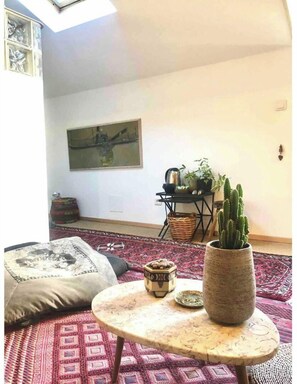 A cozy living room with a round coffee table, a potted cactus, and a patterned rug.