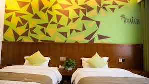 Camera d'hotel con due letti, un motivo geometrico sul muro e un logo.