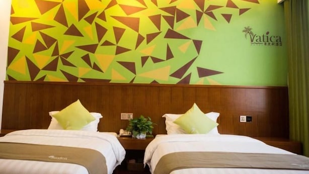 Camera d'albergo con due letti e un motivo geometrico sul muro, con il marchio 'Yatica' ben visibile.