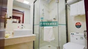 Un bagno d'albergo con box doccia in vetro, lavandino e water.