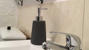 Un baño con un lavamanos blanco, un dispensador de jabón negro y un grifo cromado.