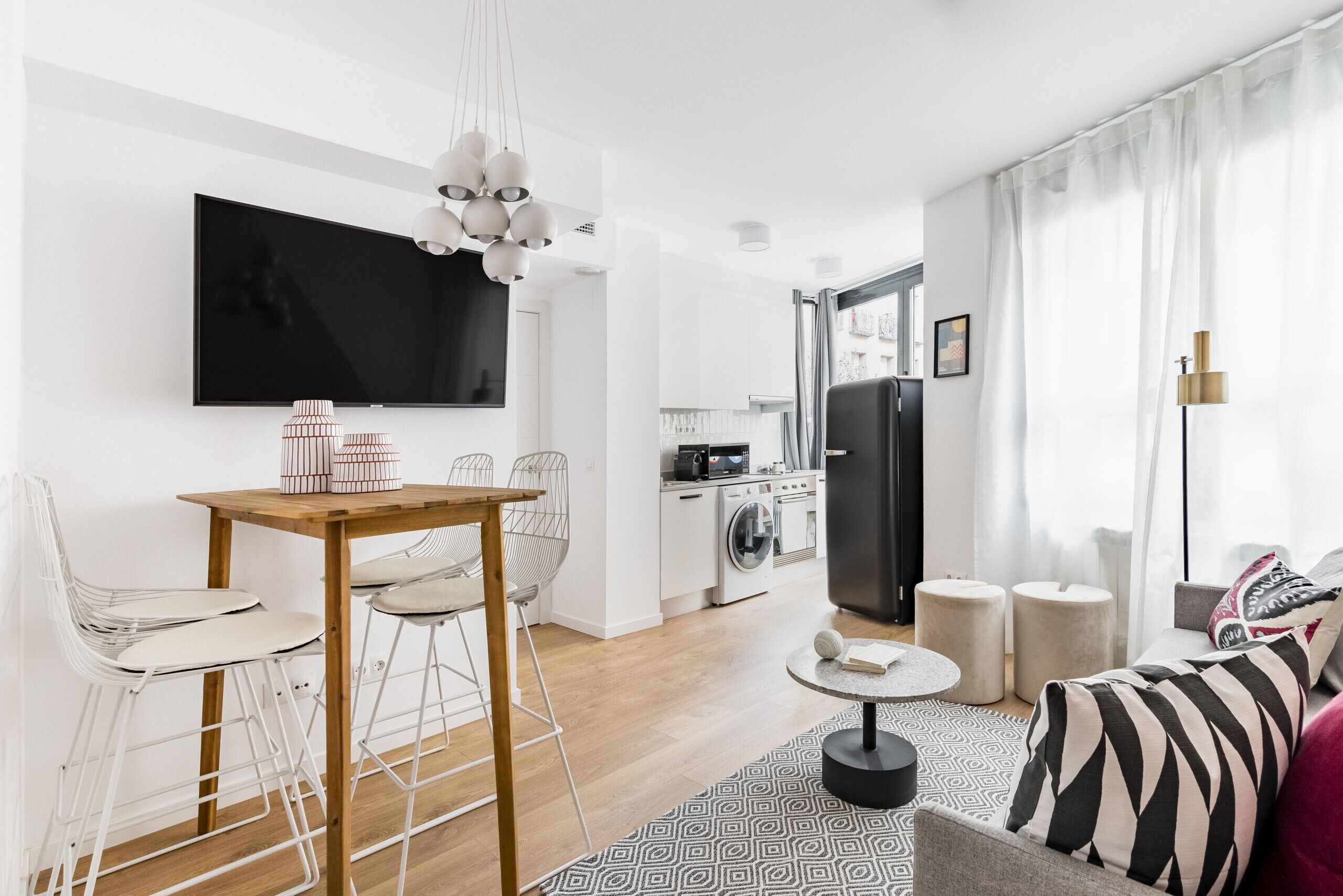 A modern living room with a dining area, kitchen, and a large TV.