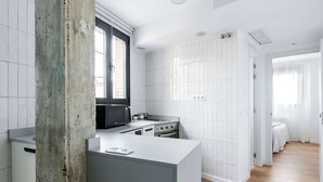 A modern kitchen with white cabinetry, a large window, and a built-in microwave.