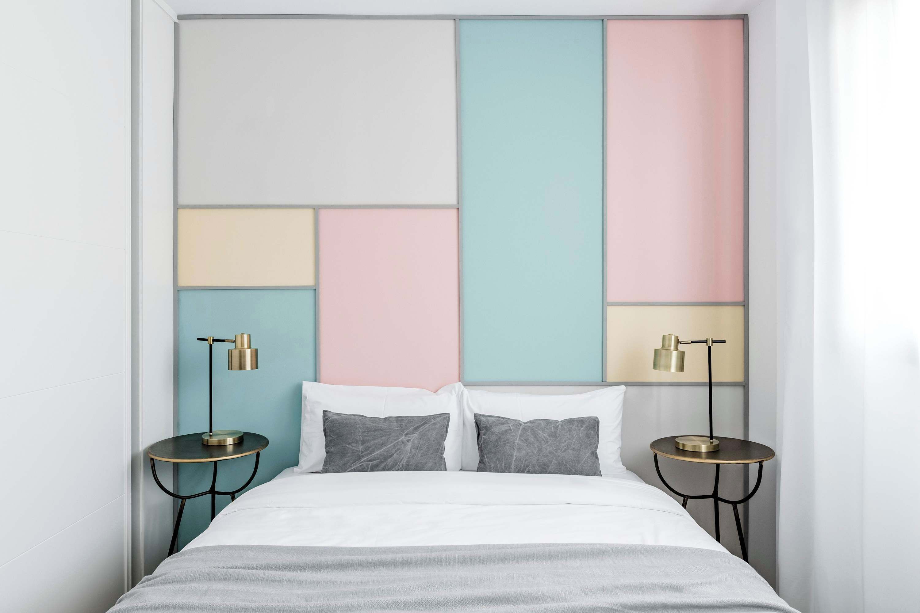 A modern bedroom with a geometric-patterned headboard, two bedside tables with lamps, and a neatly made bed.