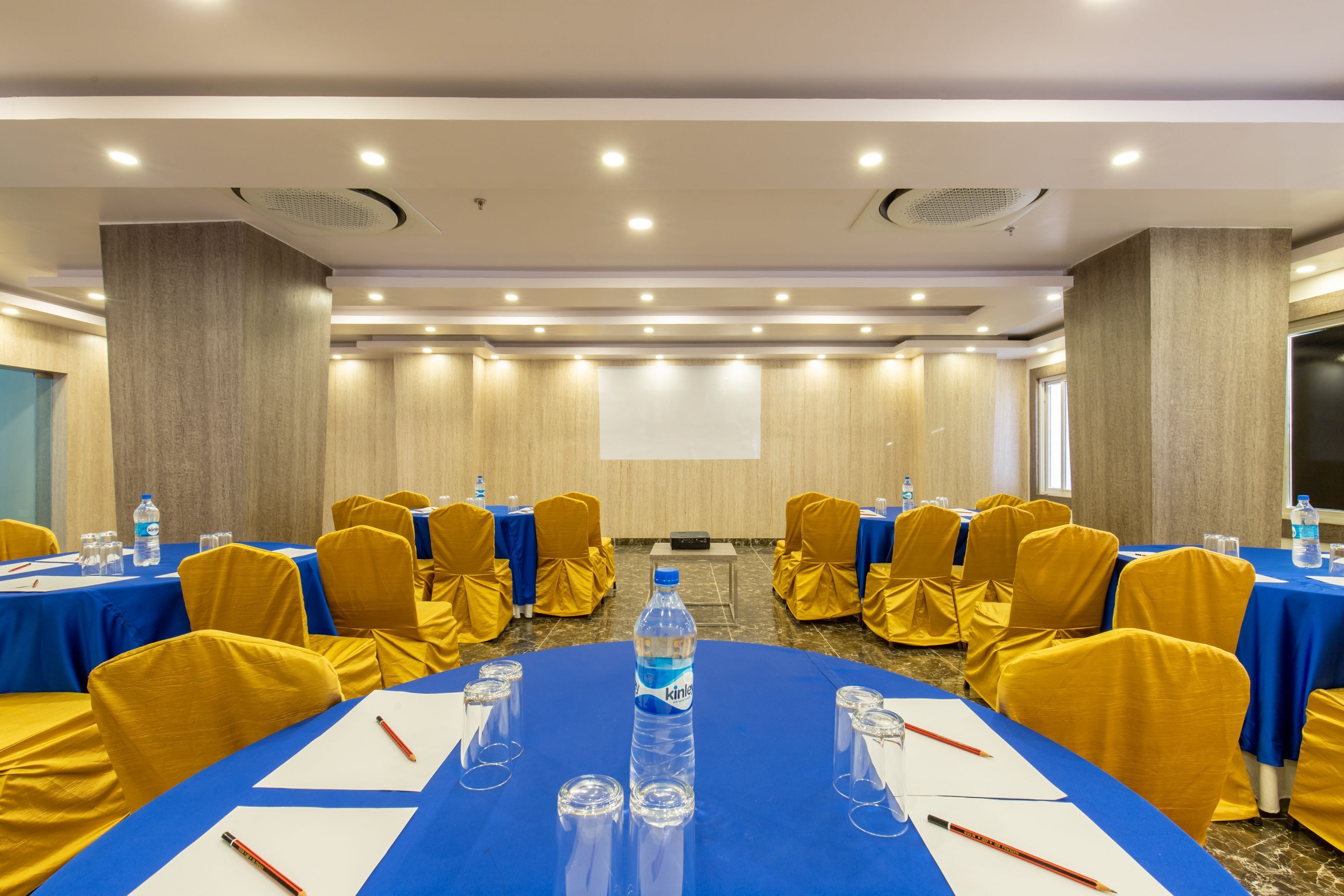 A conference room with tables set for meetings, equipped with water bottles, glasses, and pens.