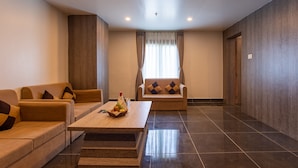 A modern living room with a sofa, armchair, and a coffee table with a fruit basket. - Hotel Maxx (Kohalpur)
