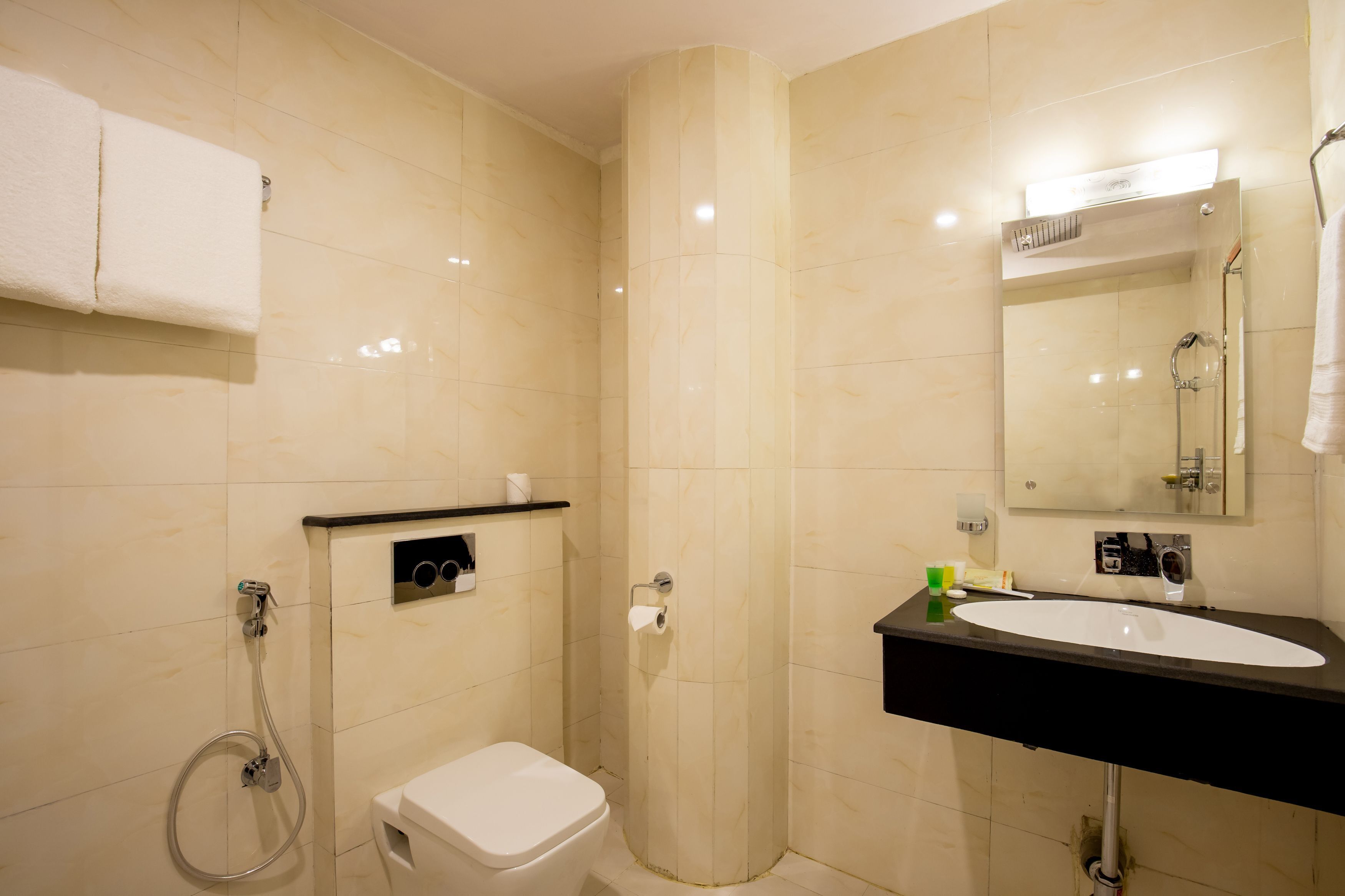 A bathroom with a toilet, sink, mirror, towel rack, and shower.