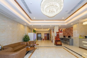 Un vestíbulo de hotel con candelabro, zona de estar, mostrador de recepción y una pared decorada con troncos de madera.