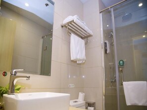 Un baño moderno con un lavamanos grande, inodoro y cabina de ducha con mampara de vidrio.