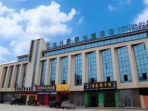Un edificio de varios pisos con grandes ventanales y letreros que indican un cine y un restaurante.