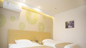 Habitación de hotel con dos camas, cabecera, unidad de aire acondicionado, teléfono sujeto a la pared y un cuadro enmarco.