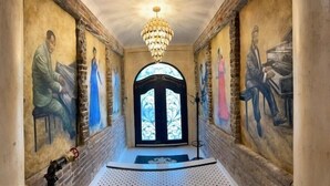 Ein Flur mit einer Chandelier, einer Glastür und Wandmalereien.