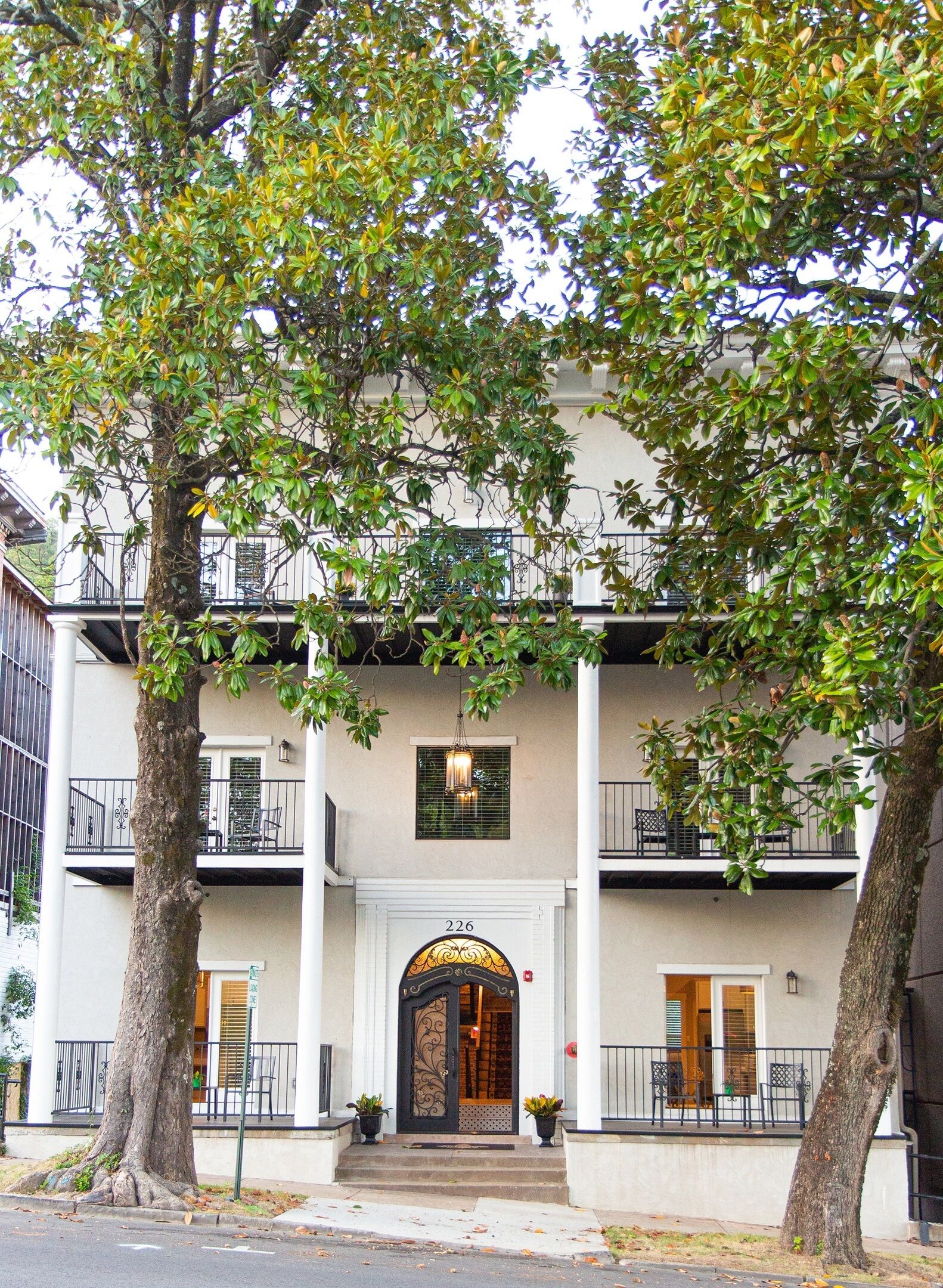 A two-story building with a central entrance, balconies, and potted plants.