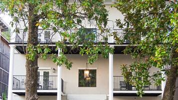 A two-story building with a central entrance, balconies, and potted plants.
