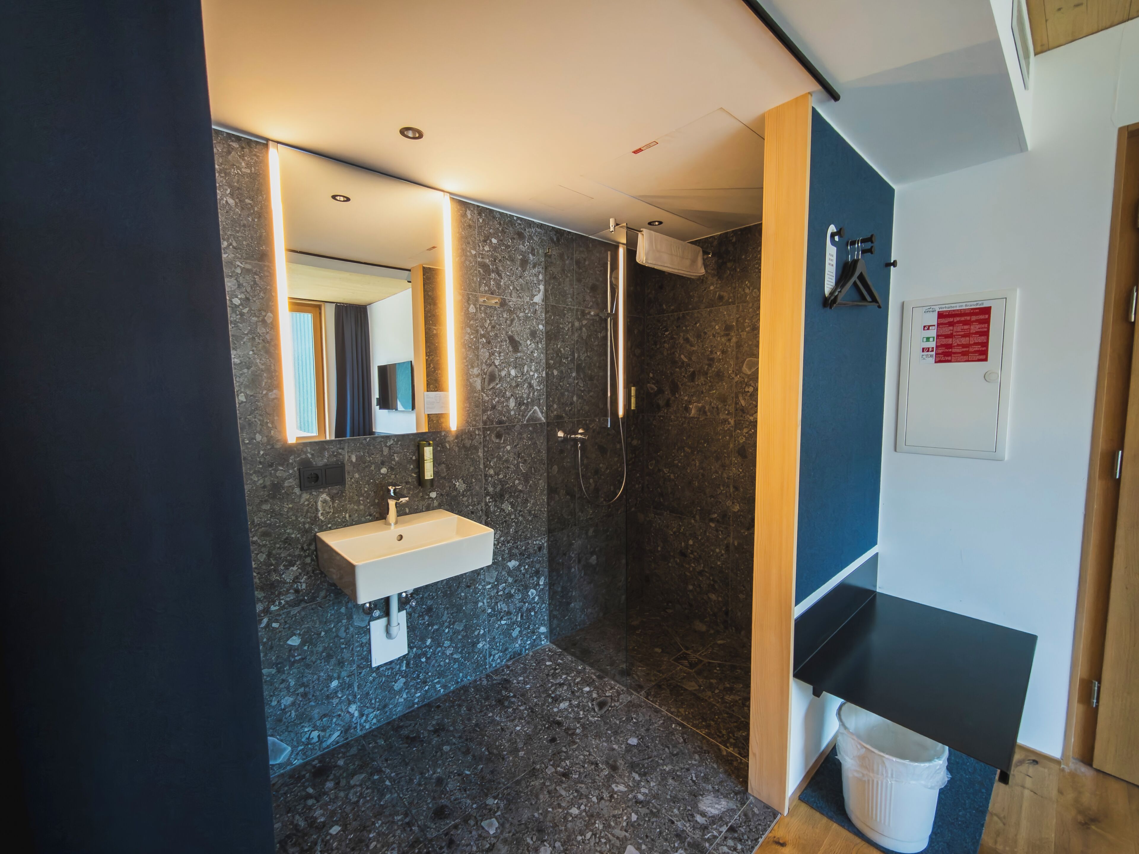 Un baño moderno con lavamanos de mármol, ducha y espejo.