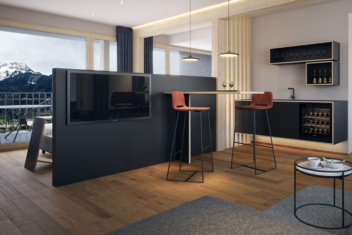 Una cocina moderna con barra, suelo de madera y un ventanal con vistas a una montaña nevada.