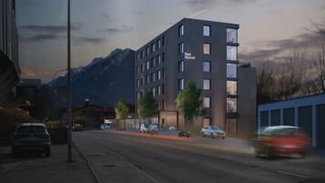 Ein modernes Hotel mit schlichter Fassade, zahlreichen Fenstern und einem Schild, das es als Hotel Alpstadt kennzeichnet.
