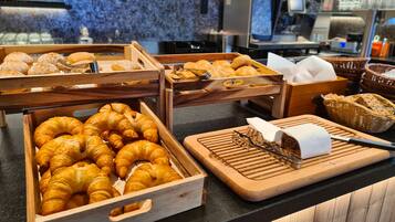 A bakery display with various baked goods, including croissants and bread, in wooden crates.